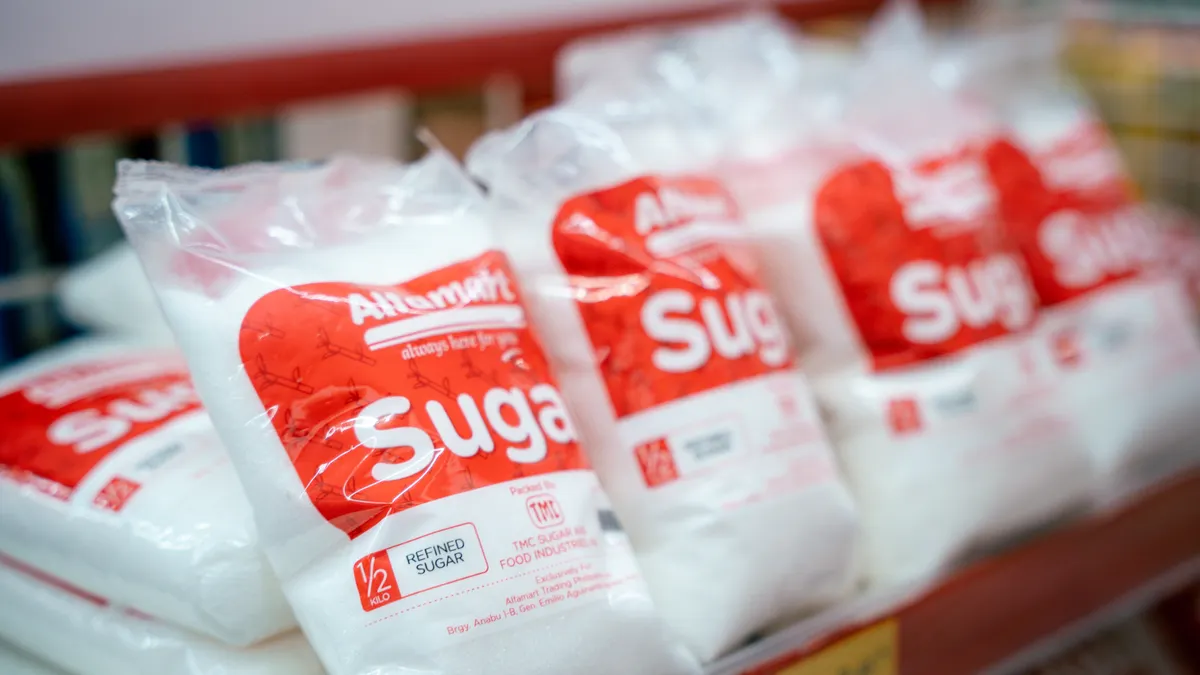 Close-up of sugar bags on a grocery store shelf, highlighting product packaging.