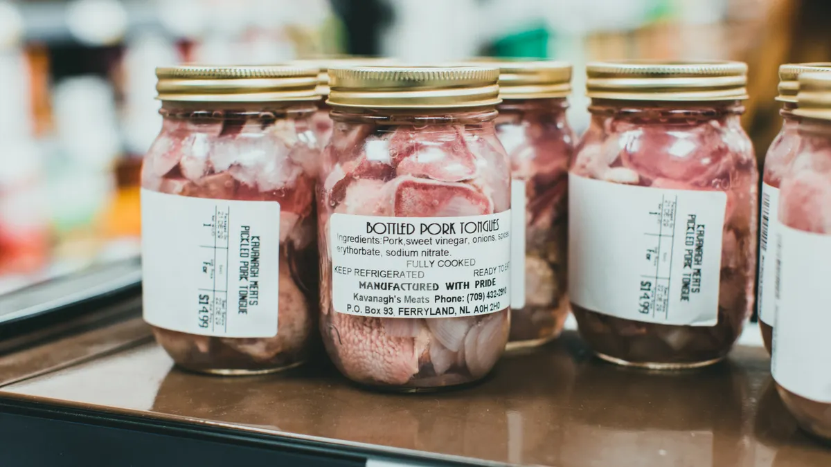 Detailed close-up shot of bottled pork tongues on display in a supermarket.