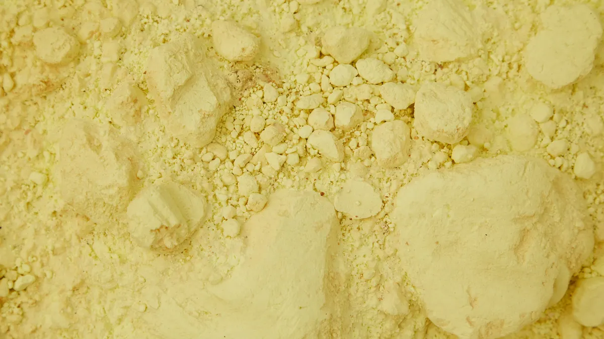 Full frame top view of clean yellow sand with ribbed stones chaotically spread around