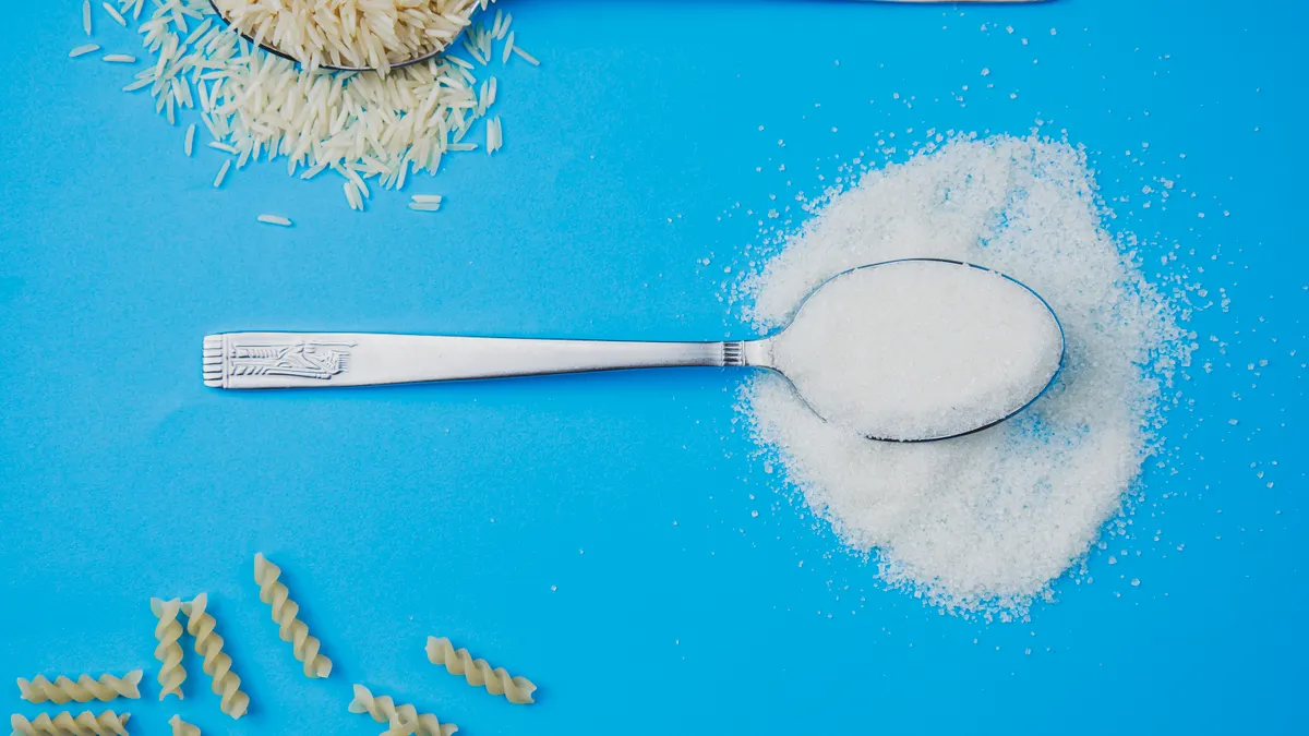 Sugar, rice, and pasta in spoons on a vivid blue surface. Perfect for food-related projects.